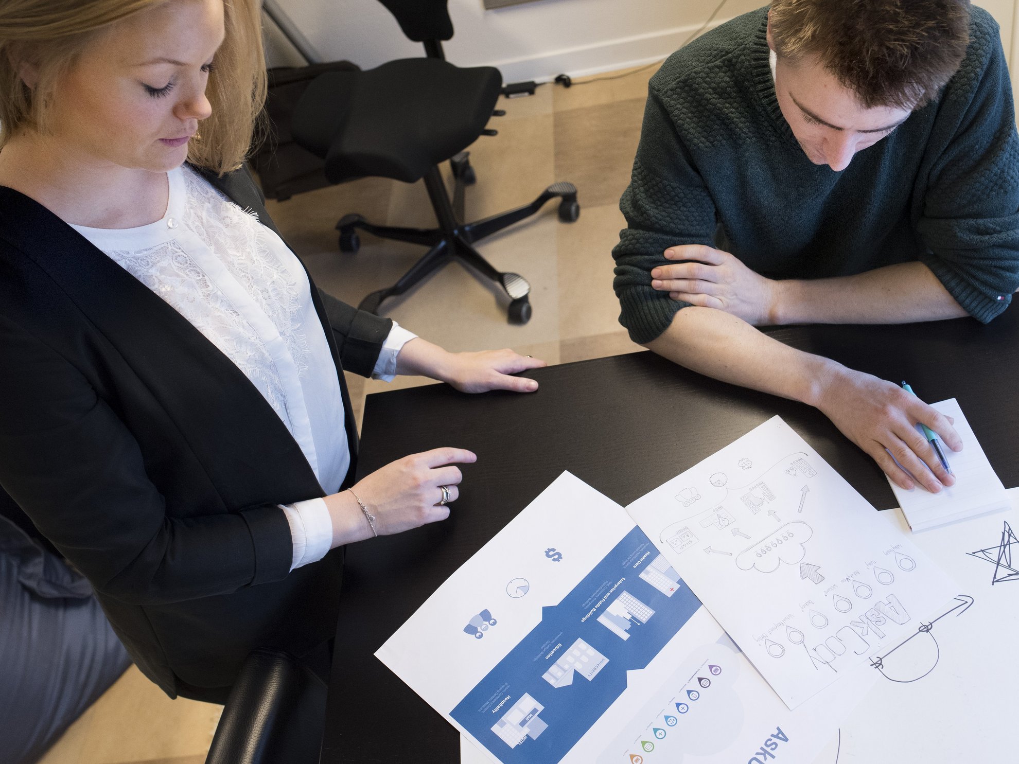 Kvinde og mand kigger på papir med illustrationer.