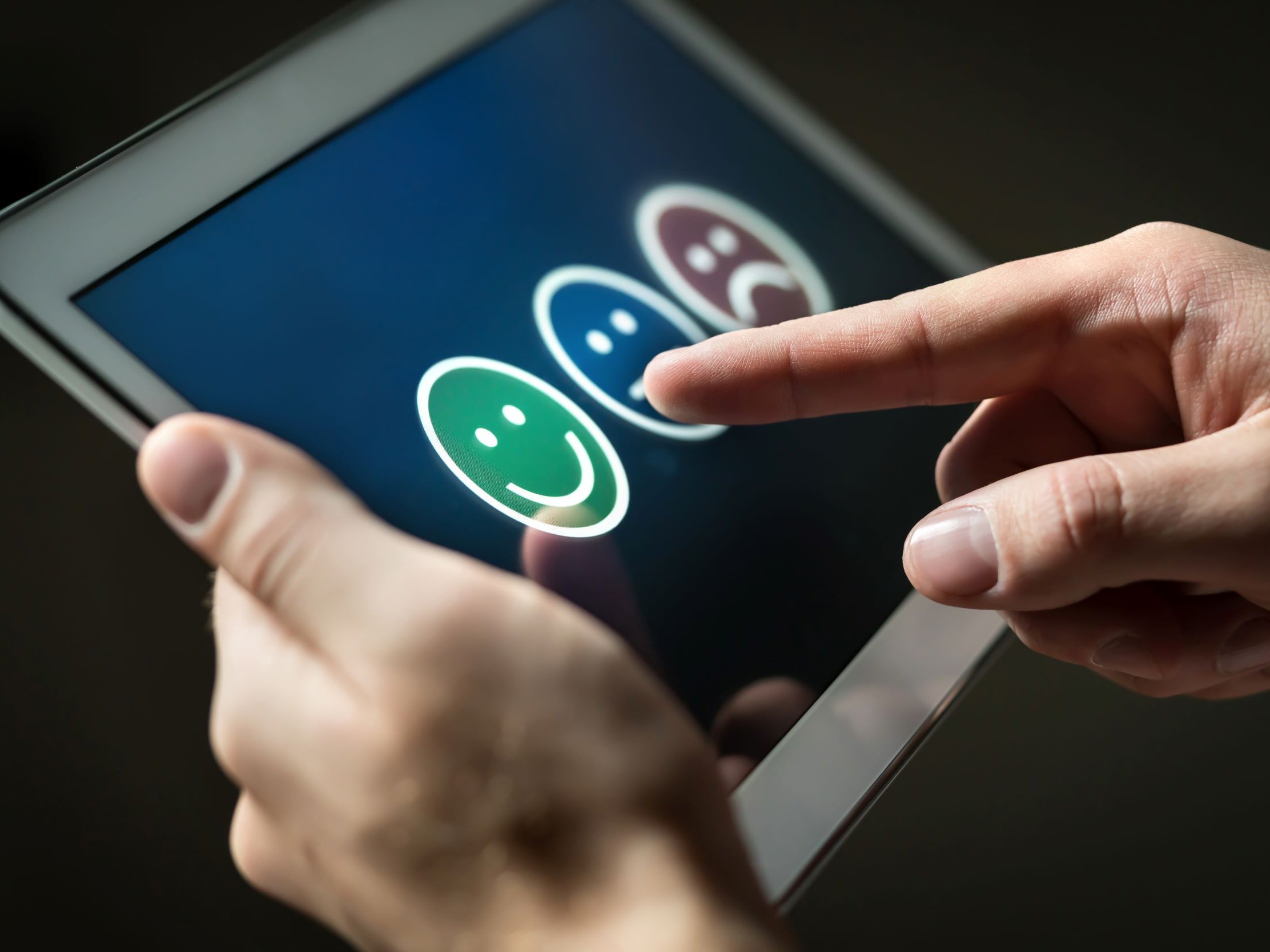 Person holder tablet med glad, neutral og sur smiley. Colourbox, #185712.